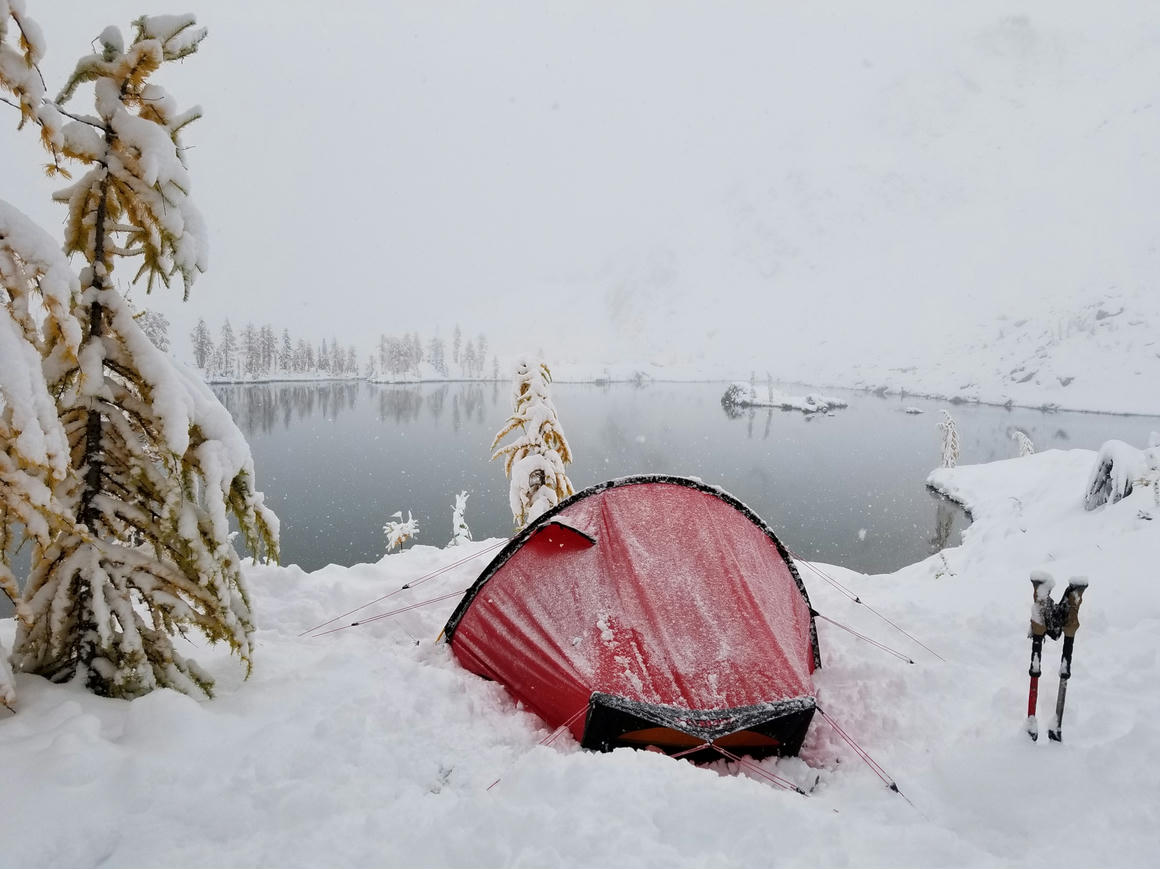 Howard's red tent surrounded by freshly fallen snow during a September photography trip at a remote alpine lake in the Bugaboos, Canadian Rockies