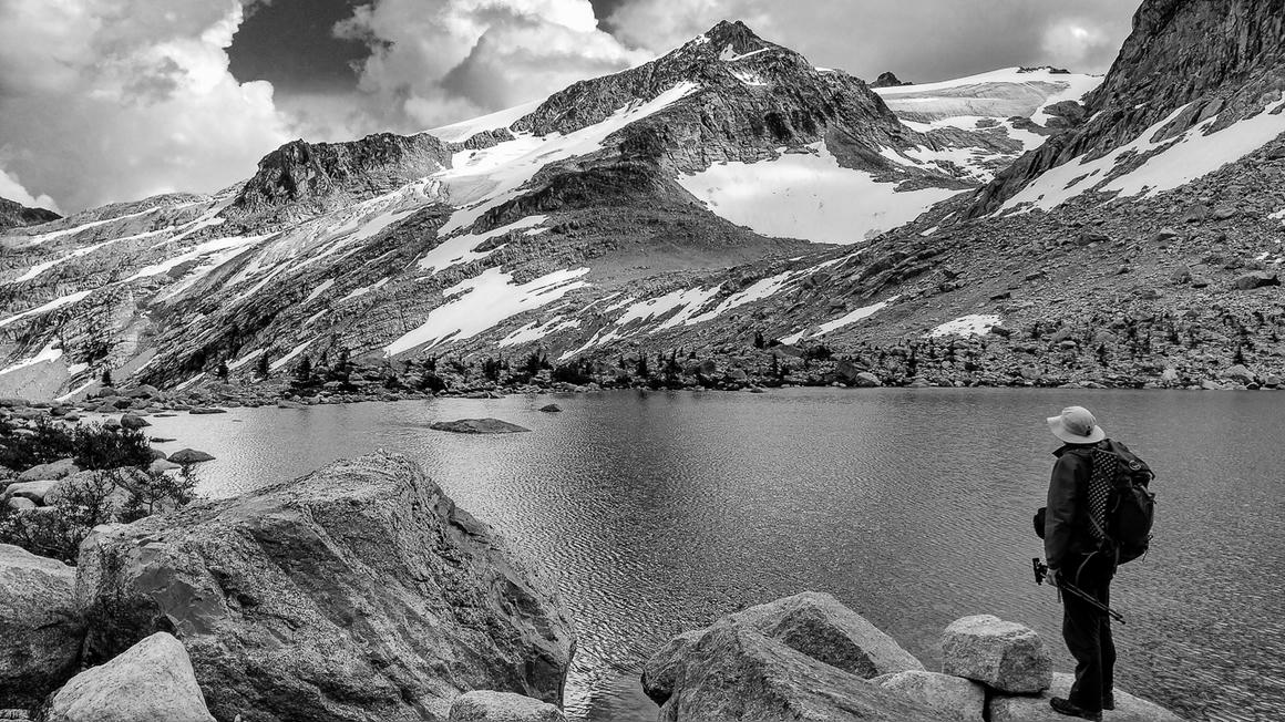Howard scouting the scene at Thunderwater Lake, with the glacial lake and Thunderwater Glacier in view amidst the dramatic alpine terrain